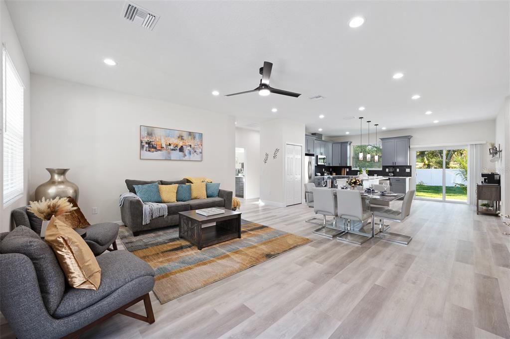 An open-concept living and dining area features gray flooring, a modern kitchen, and sliding doors — 6510 E 25TH AVENUE, TAMPA, FL