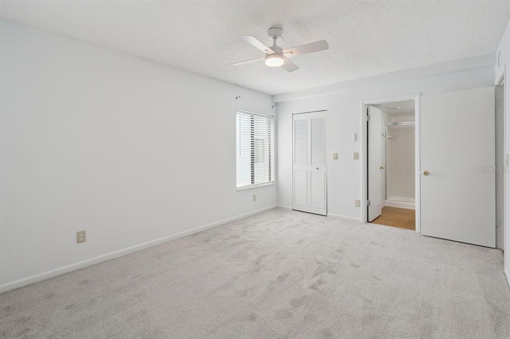 A bedroom with white walls, gray carpeting, a ceiling fan, and an attached bathroom — 8215 SUN SPRING CIRCLE UNIT 12, ORLANDO, FL