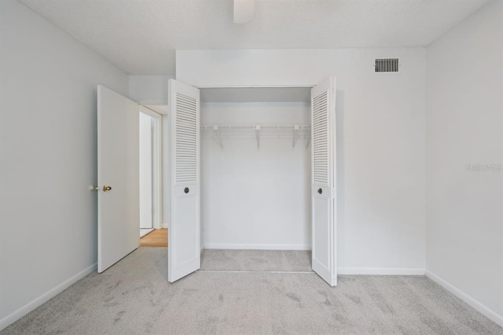 A bedroom features gray carpet, white walls, a closet with louvered doors, and an open doorway — 8215 SUN SPRING CIRCLE UNIT 12, ORLANDO, FL