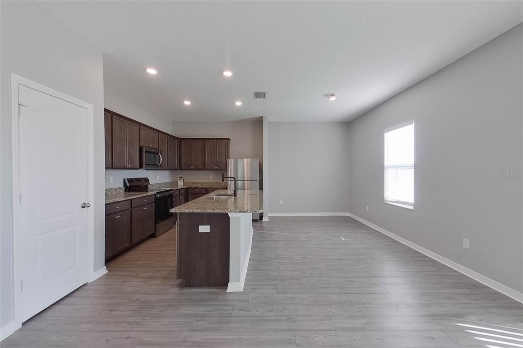 A kitchen with dark wood cabinets, granite countertops, and light gray wood-look flooring — 30098 FEDORA CIRCLE, BROOKSVILLE, FL