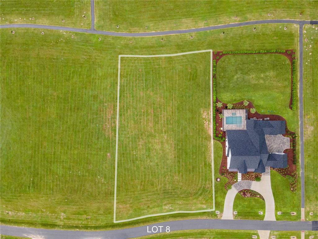 An aerial view shows a vacant rectangular lot next to a house with a pool — 5118 SW 125TH CIRCLE, ARCHER, FL