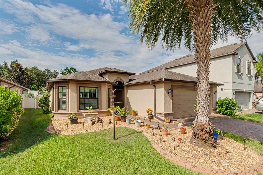 A single-story suburban house with a tan exterior, a palm tree, and a gravel front yard — 14219 STOCKWELL LANE, RUSKIN, FL