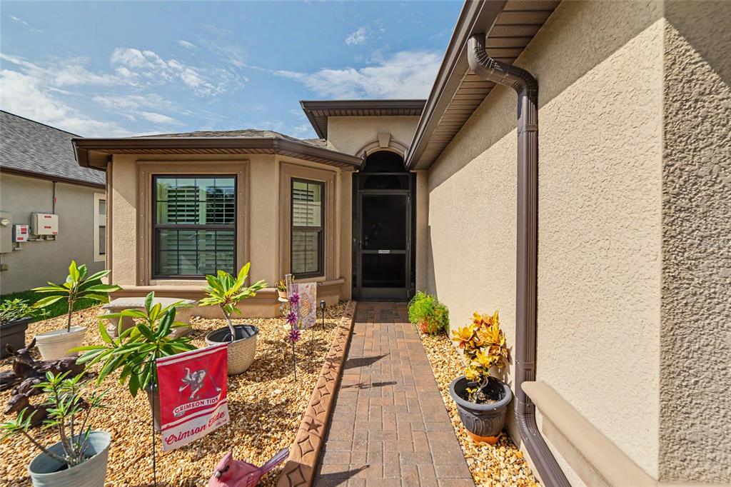A front entryway features a dark door with a wreath, brick flooring, and decorative figurines — 14219 STOCKWELL LANE, RUSKIN, FL