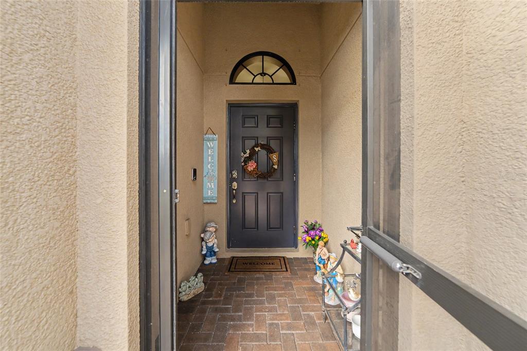 An entryway features a white door, a black console table, and wall decor on tan walls — 14219 STOCKWELL LANE, RUSKIN, FL