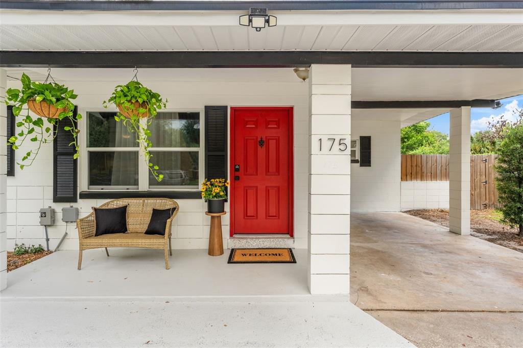 A white house exterior features a bright red front door, a wicker bench, and carport — 175 GRACE BOULEVARD, ALTAMONTE SPRINGS, FL