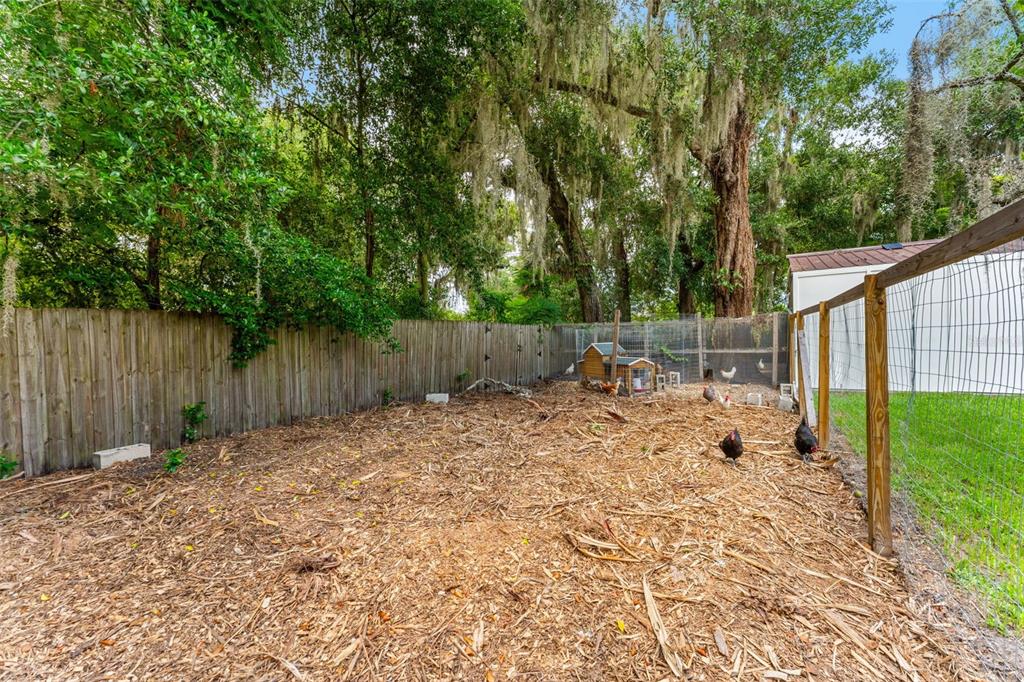 Two raised wooden garden beds sit on a wood-chipped path beside a white building — 175 GRACE BOULEVARD, ALTAMONTE SPRINGS, FL