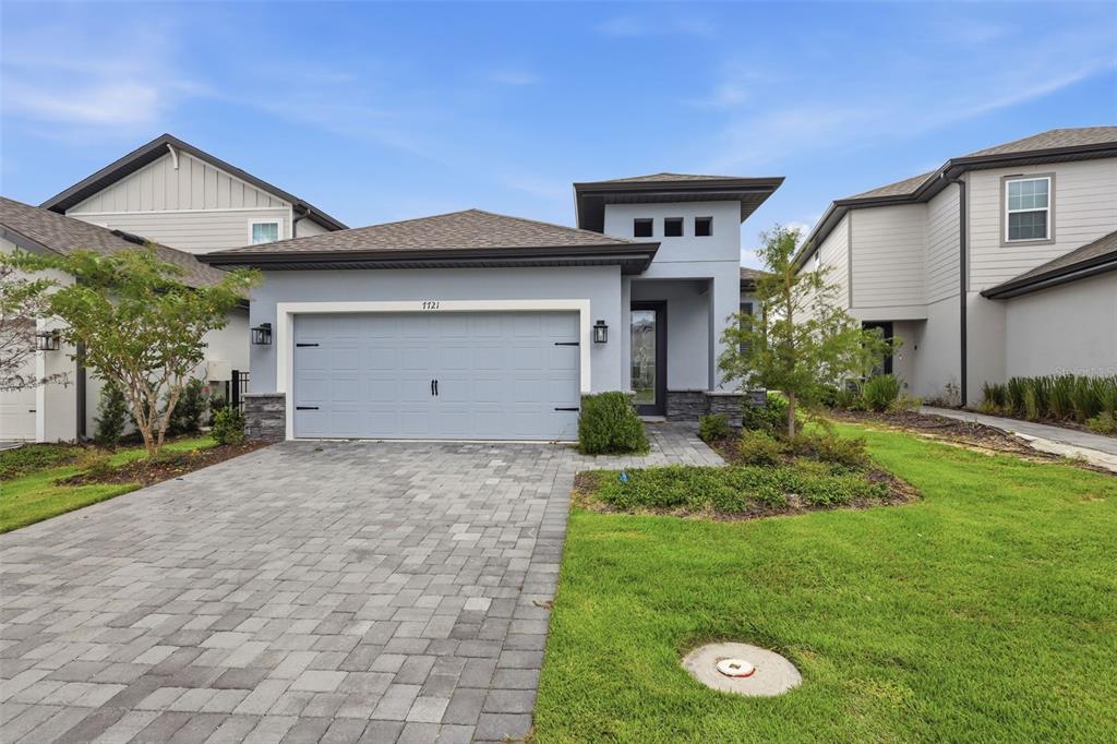 A single-story house with a light blue exterior, a two-car garage, and a paved driveway — 7721 SOMERSWORTH DRIVE, KISSIMMEE, FL
