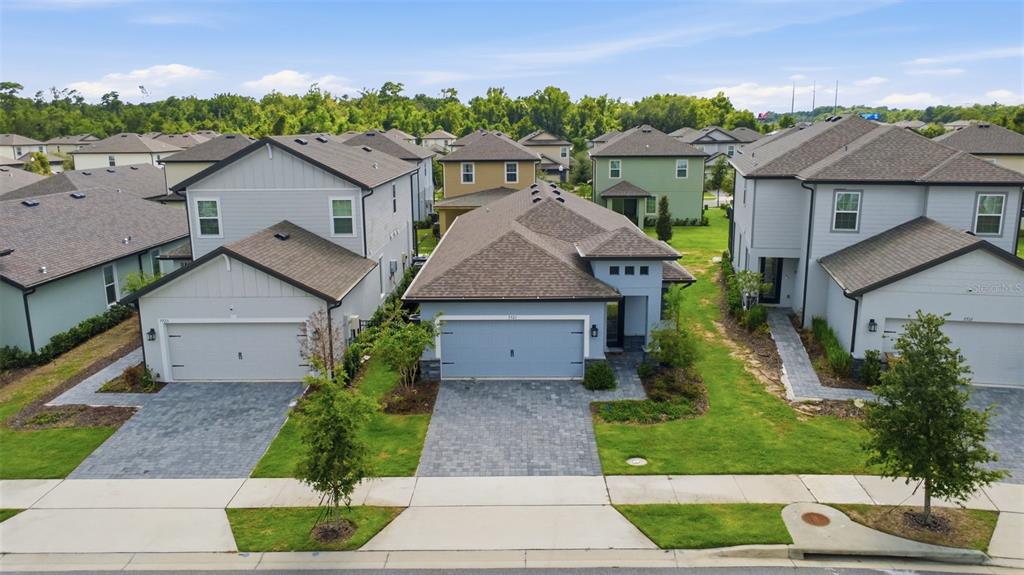 An aerial view shows three suburban houses with paved driveways and green lawns — 7721 SOMERSWORTH DRIVE, KISSIMMEE, FL
