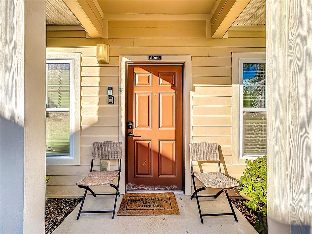 A front entrance features a brown door, two chairs, and a welcome mat — 8986 SHINE DRIVE, KISSIMMEE, FL