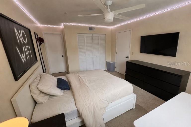 A bedroom features a bed, a black dresser with a television, and white closet doors — 2360 SW ARCHER ROAD UNIT 915, GAINESVILLE, FL