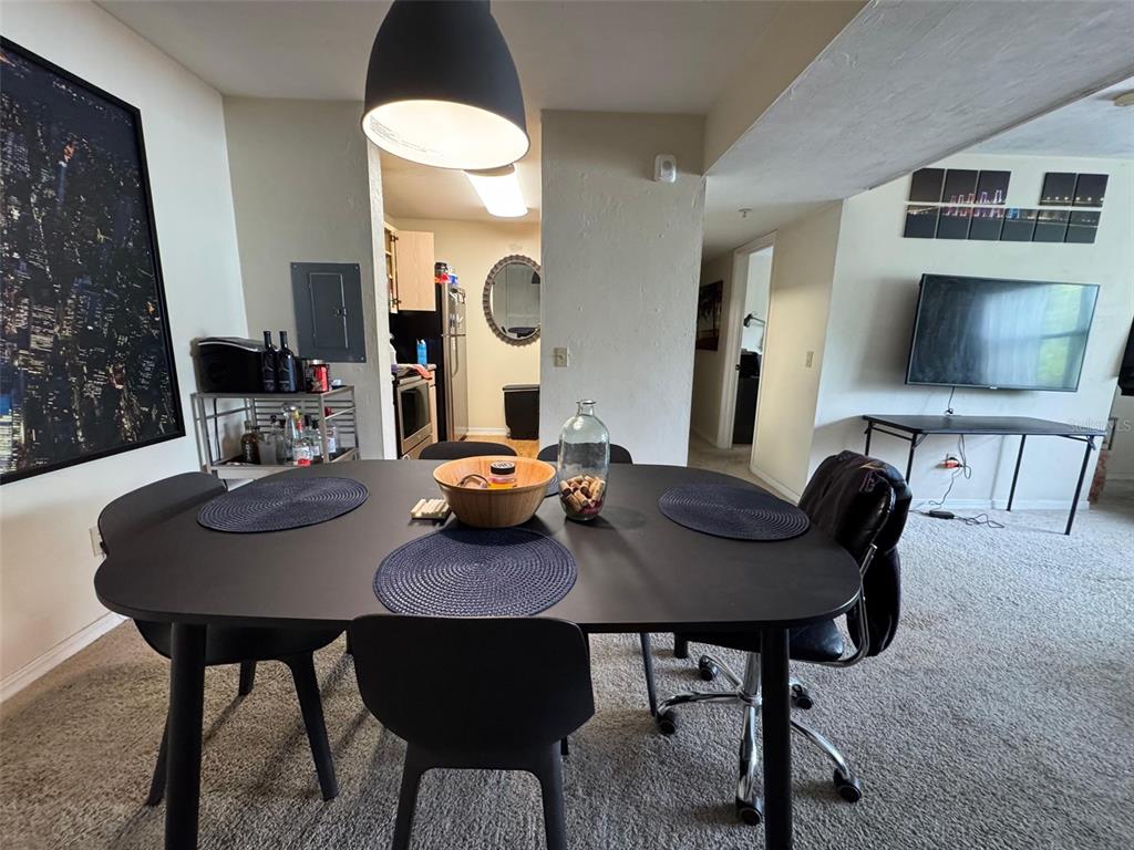 A dining area with a black table, chairs, and a pendant light overlooks a kitchen — 2360 SW ARCHER ROAD UNIT 915, GAINESVILLE, FL