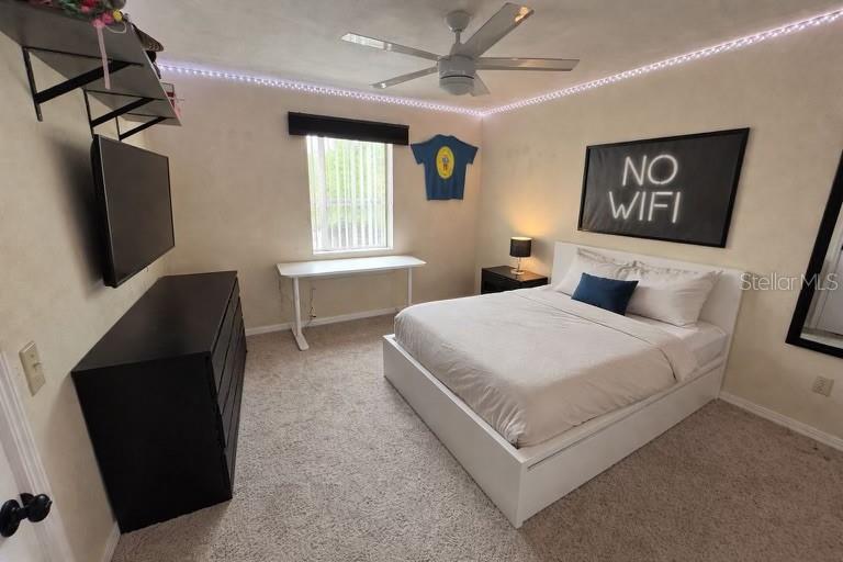 A bedroom features a white bed, a black dresser, a desk, and a ceiling fan — 2360 SW ARCHER ROAD UNIT 915, GAINESVILLE, FL