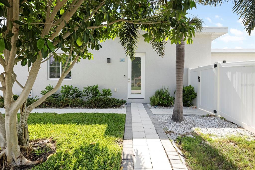 A paved walkway leads to the front entrance of a house with a white fence — 4524 RIVERWOOD AVENUE, SARASOTA, FL