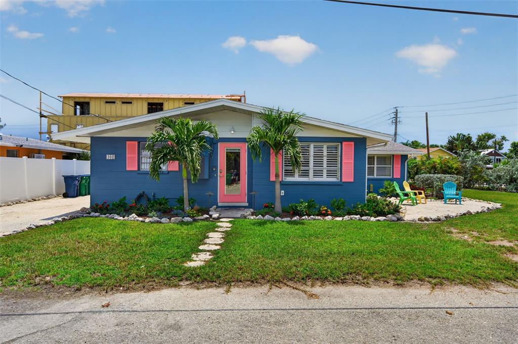 A blue house with pink shutters and a pink front door sits on a grassy lot — 401 63RD STREET, HOLMES BEACH, FL