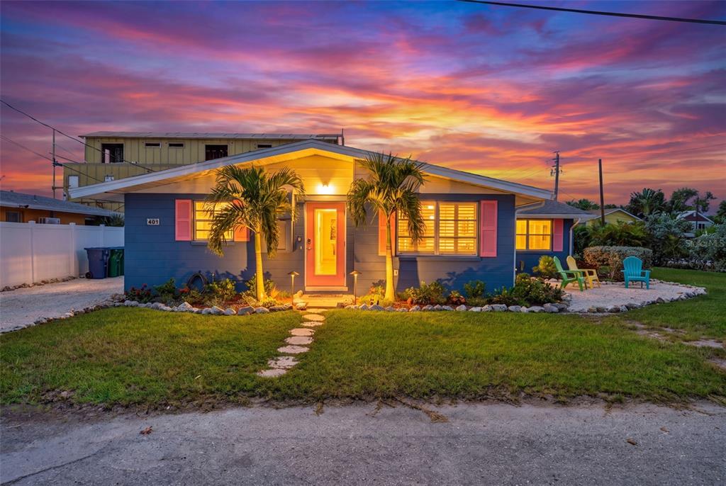 A blue single-story house with pink shutters and a bright orange front door at sunset — 401 63RD STREET, HOLMES BEACH, FL