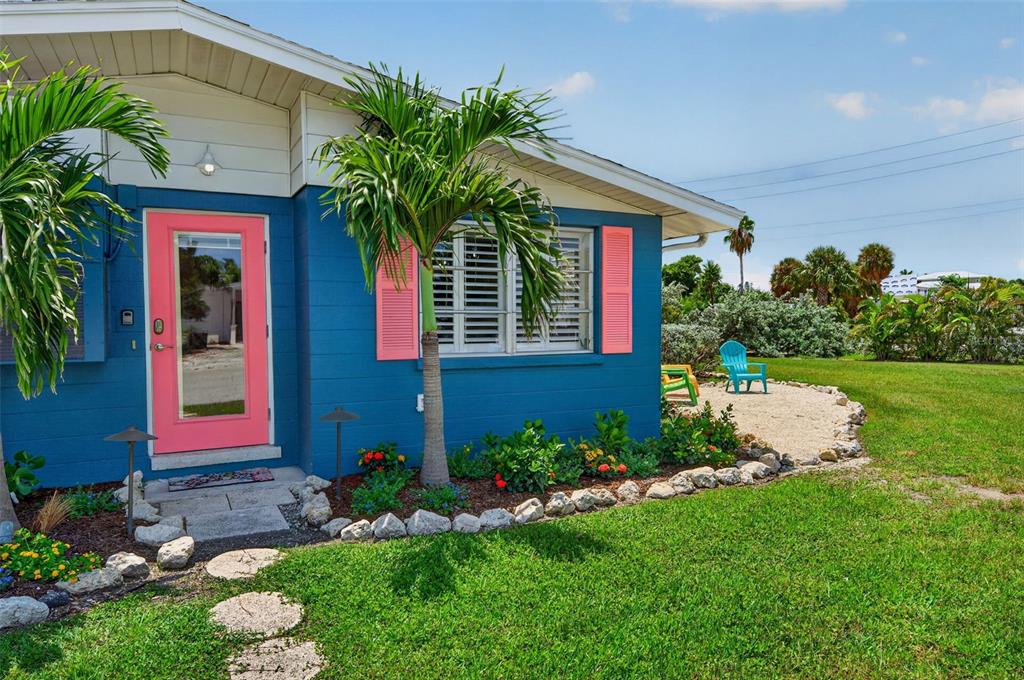 A blue house exterior features a bright pink door, pink shutters, and a palm tree — 401 63RD STREET, HOLMES BEACH, FL
