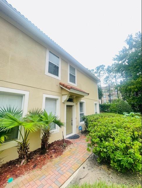 A beige two-story building features a brick walkway, palm plants, and a small front porch — 3602 SHALLOT DRIVE UNIT 106, ORLANDO, FL
