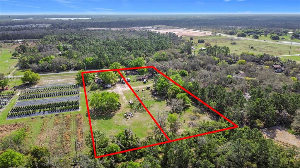 An aerial view shows two adjacent rectangular lots outlined in red amidst trees and fields — 2360 ABSHER ROAD, ST CLOUD, FL