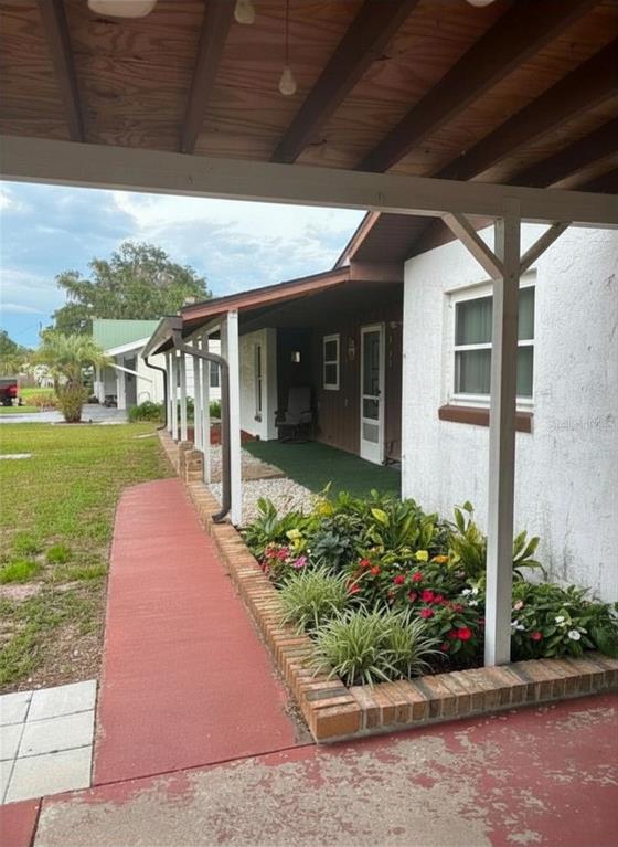 A covered patio features a red painted floor, a brick planter, and a walkway — 919 CR 482D, LAKE PANASOFFKEE, FL
