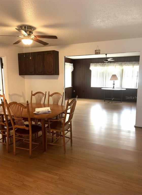 A dining area with a wooden table and chairs opens into a living room — 919 CR 482D, LAKE PANASOFFKEE, FL