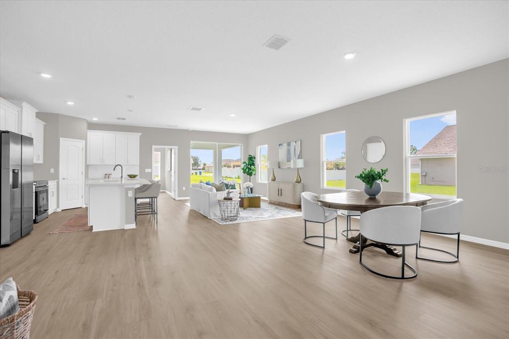An open-concept living area features a kitchen with white cabinetry, a dining space, and flooring — 5834 ESCALON DRIVE, SEBRING, FL