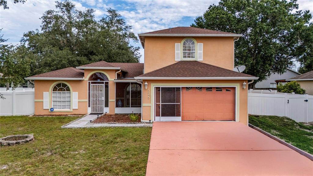 A two-story peach-colored house with a brown roof, a garage, and a white fence — 525 FINCH LANE, POINCIANA, FL