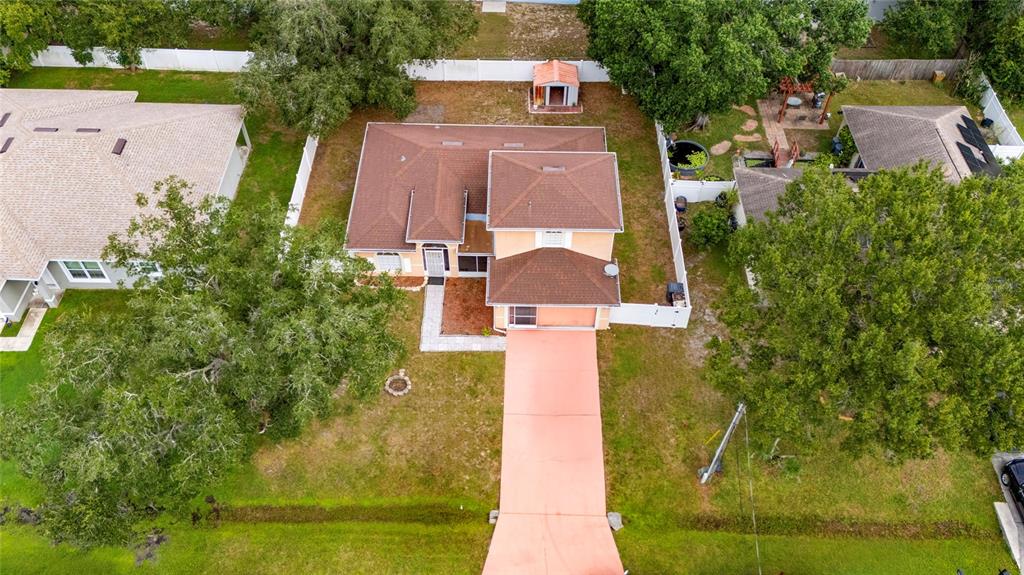 An aerial view shows a single-story house with a brown roof and a long driveway — 525 FINCH LANE, POINCIANA, FL