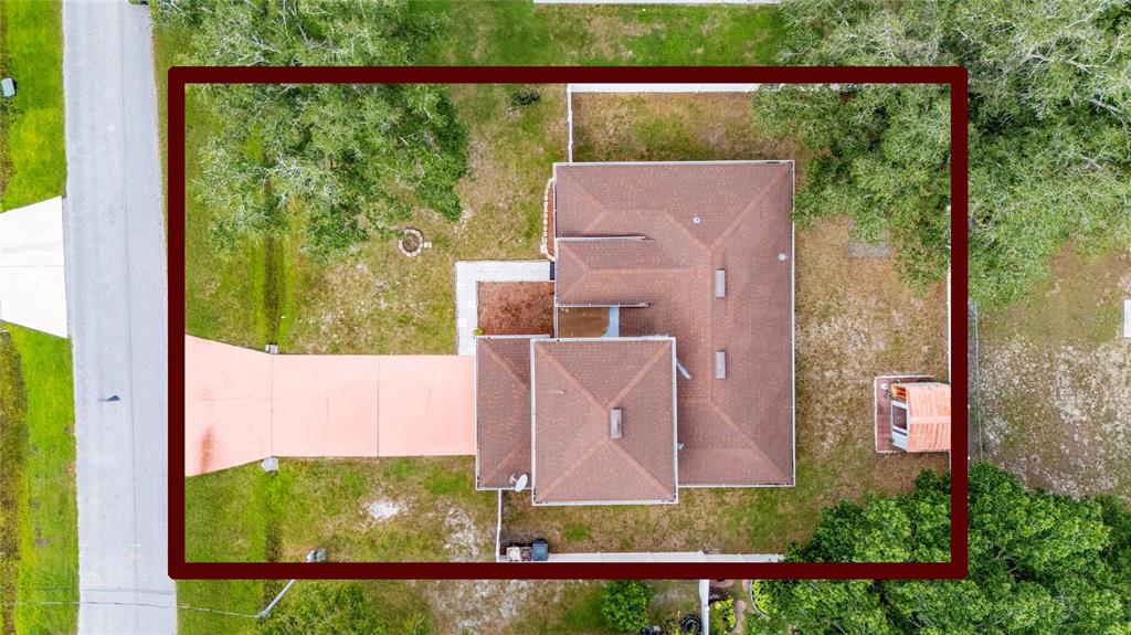 An aerial view shows a house with a brown roof, a driveway, and surrounding trees — 525 FINCH LANE, POINCIANA, FL
