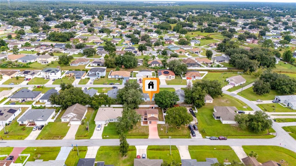 An aerial view shows a suburban neighborhood with a highlighted single-family house and surrounding homes — 525 FINCH LANE, POINCIANA, FL