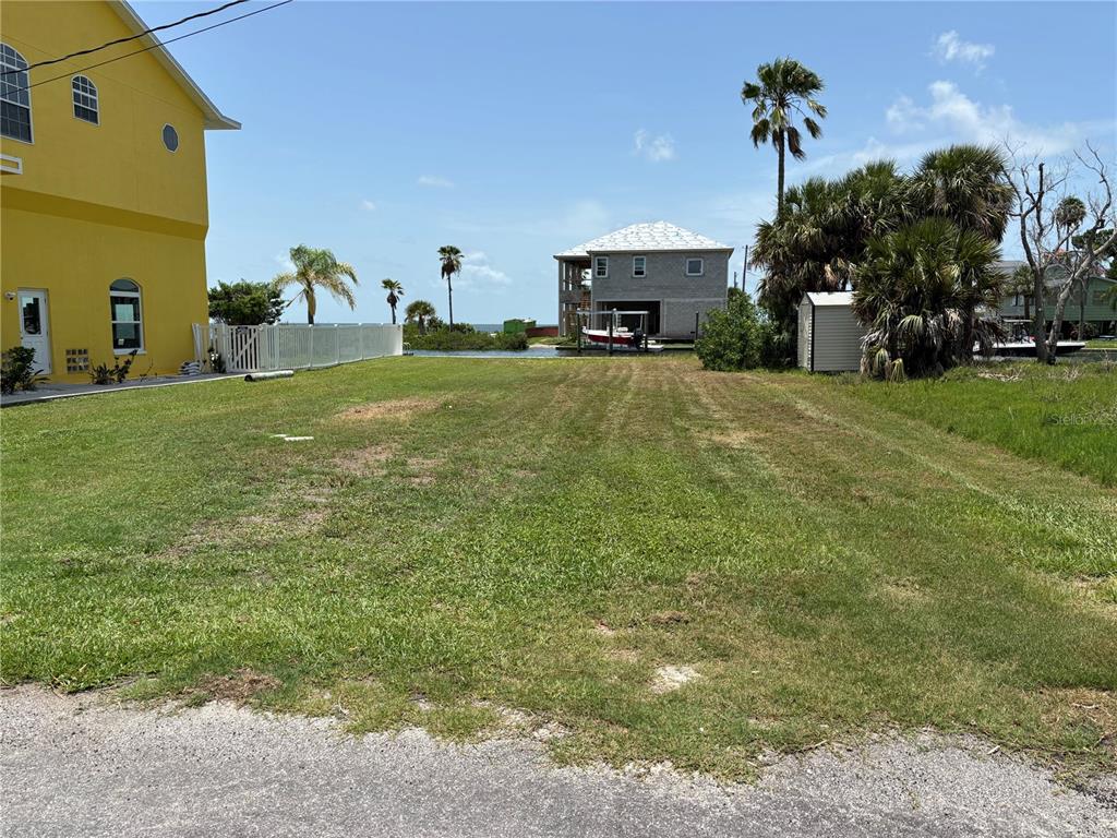 A vacant, grassy waterfront lot sits between a yellow house and a shed — 0 SEAVIEW BOULEVARD, HUDSON, FL