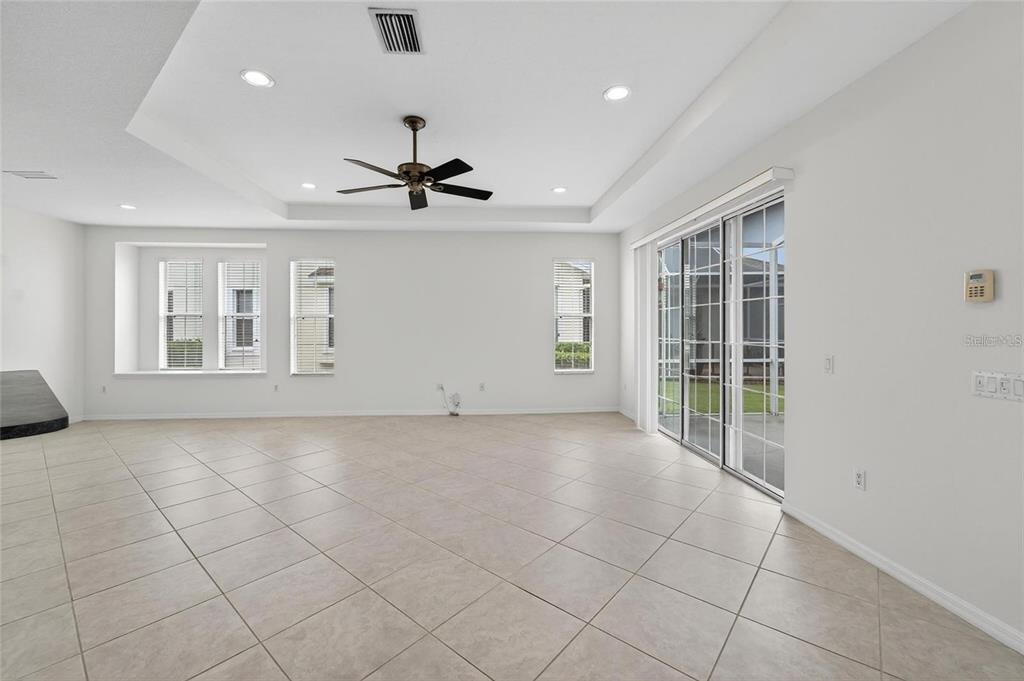 A spacious living room with tile flooring, a tray ceiling, and sliding glass patio doors — 209 SELA COVE CIRCLE, APOLLO BEACH, FL