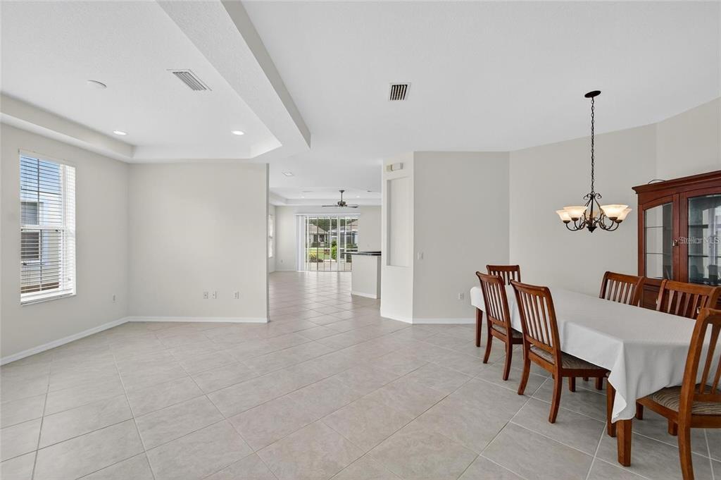 A dining area with tile floors, a wooden table, and a view into the living space — 209 SELA COVE CIRCLE, APOLLO BEACH, FL