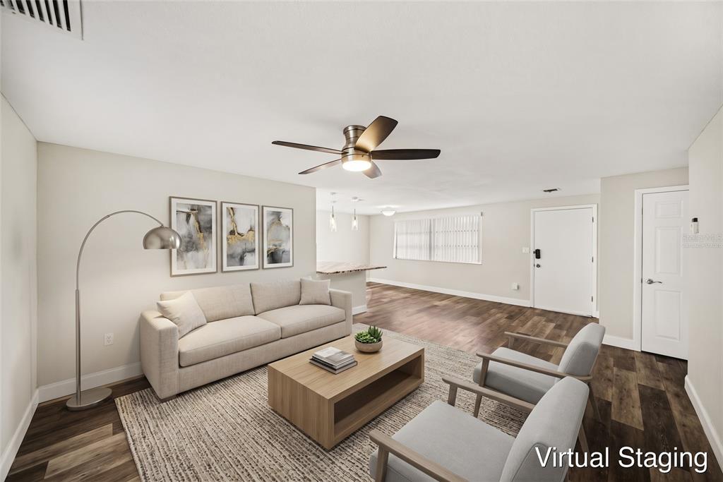 An open-concept living area features wood-look flooring, a ceiling fan, and a kitchen breakfast bar — 7541 SPIREA DRIVE, PORT RICHEY, FL