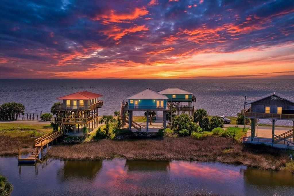 An aerial view of three stilt houses along a waterfront at sunset — 19018 GOOD TIMES DRIVE, PERRY, FL