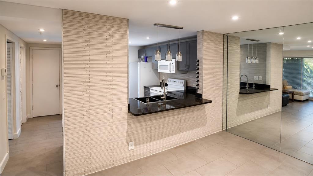 A kitchen with dark cabinets and a granite breakfast bar features textured wall paneling — 8810 W MCNAB ROAD UNIT 303, TAMARAC, FL