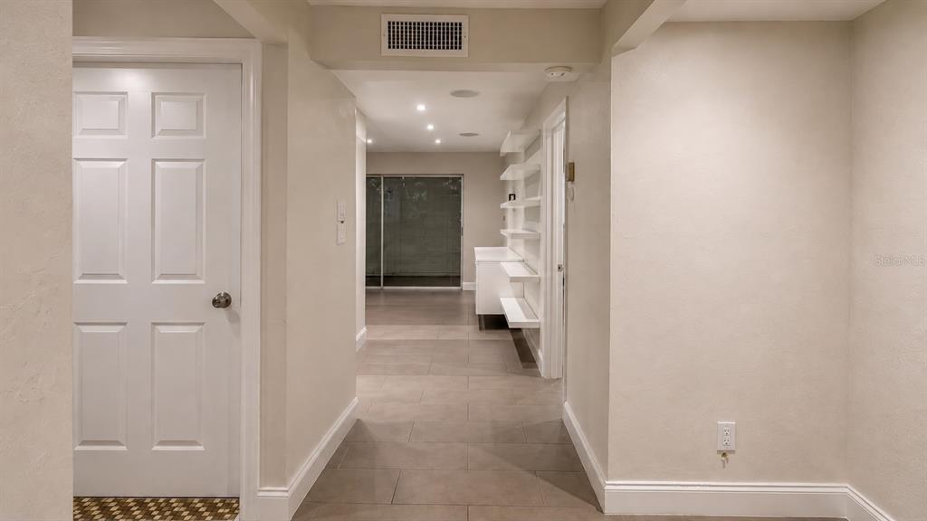 A hallway with light tile flooring leads to a room with sliding glass doors — 8810 W MCNAB ROAD UNIT 303, TAMARAC, FL