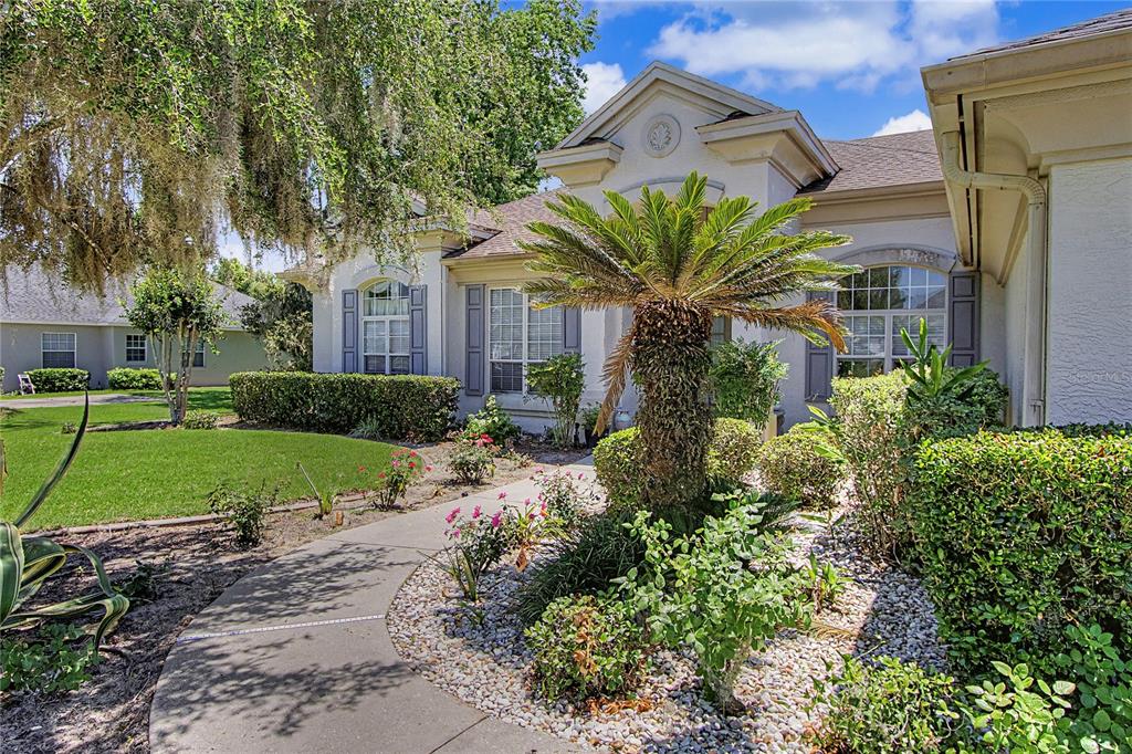 A curved concrete walkway leads to the front entrance of a single-story suburban home — 2114 SE 25TH LOOP, OCALA, FL