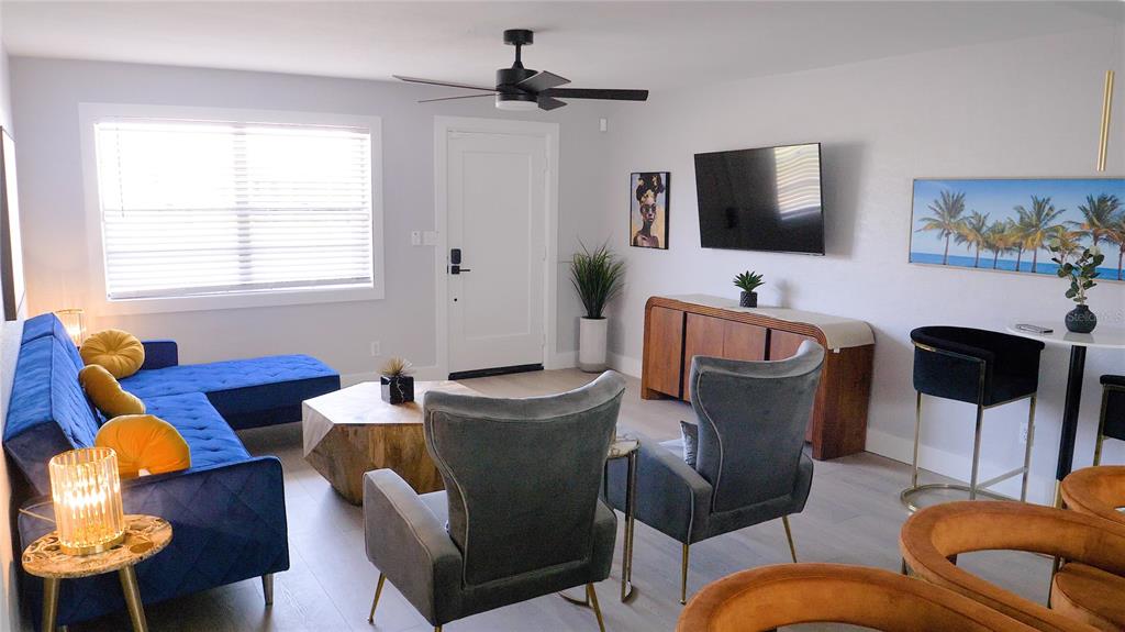 A living room features a blue sectional sofa, two gray armchairs, and a wall-mounted television — 137 N HOLLYWOOD AVENUE, DAYTONA BEACH, FL