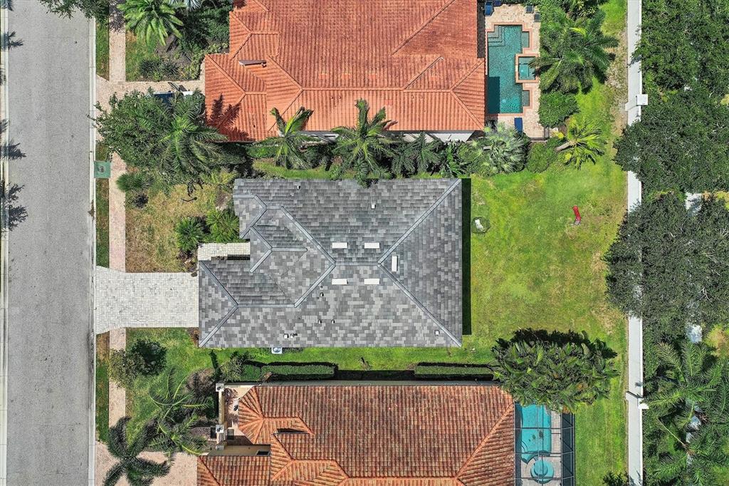 An aerial view shows a house with a gray roof situated between two homes with orange-tiled roofs — 5515 TITLE ROW DRIVE, BRADENTON, FL