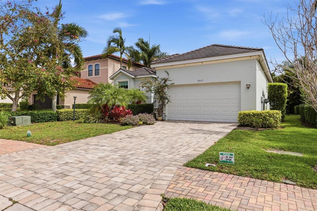 A light-colored single-story house with a paved driveway and a two-car garage — 5515 TITLE ROW DRIVE, BRADENTON, FL