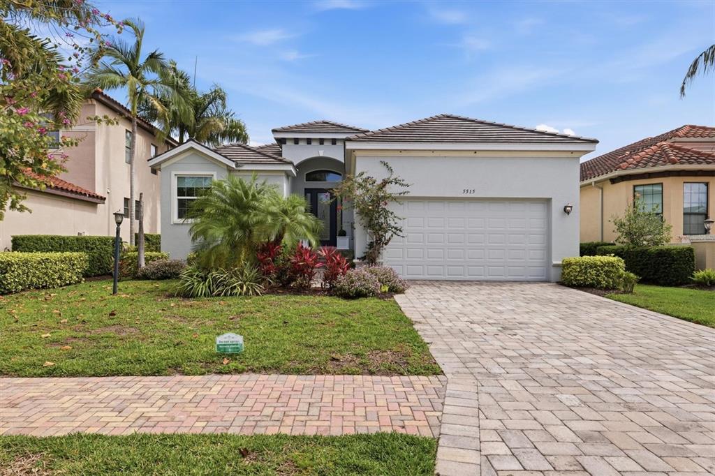 A single-story suburban house with a paved driveway, a two-car garage, and landscaped front yard — 5515 TITLE ROW DRIVE, BRADENTON, FL