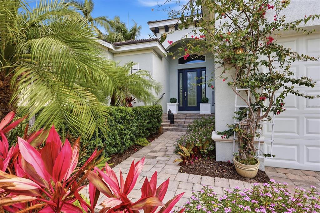 A paved walkway leads to the front entrance of a house with lush landscaping — 5515 TITLE ROW DRIVE, BRADENTON, FL