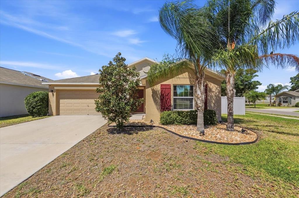 A single-story house with a tan exterior, a two-car garage, and a palm tree — 936 ZONE TAILED HAWK PLACE, RUSKIN, FL