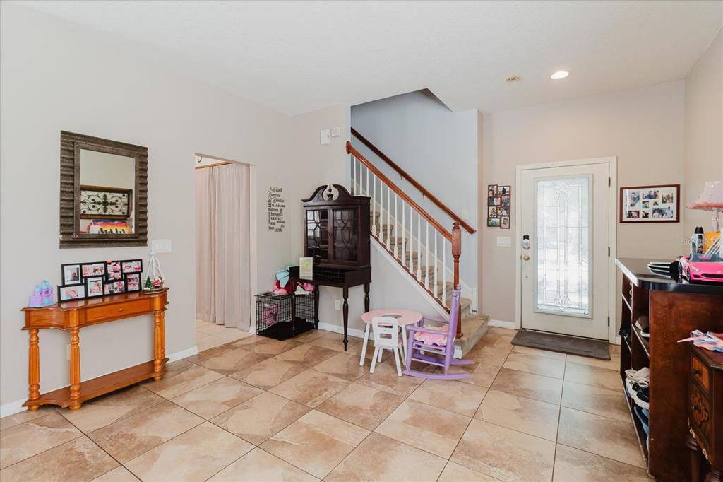An entryway features tiled floors, a staircase, a wooden console table, and a front door — 15521 LONG CYPRESS DRIVE, RUSKIN, FL