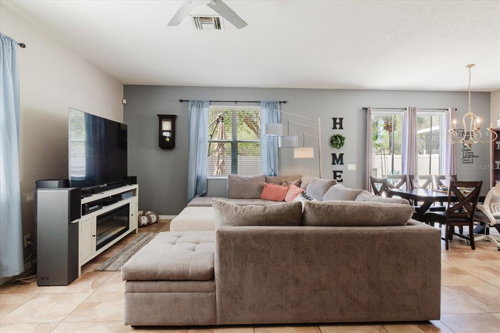 A living room features a large sectional sofa, a television console, and a dining area — 15521 LONG CYPRESS DRIVE, RUSKIN, FL