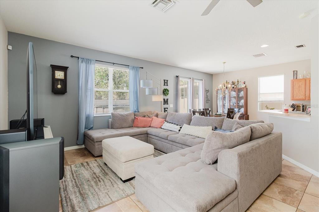 A living room features a large gray sectional sofa, a matching ottoman, and a dining area — 15521 LONG CYPRESS DRIVE, RUSKIN, FL