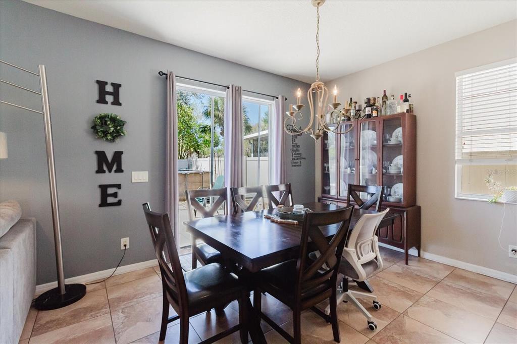 A dining room features a dark wood table, a china cabinet, and a sliding glass door — 15521 LONG CYPRESS DRIVE, RUSKIN, FL