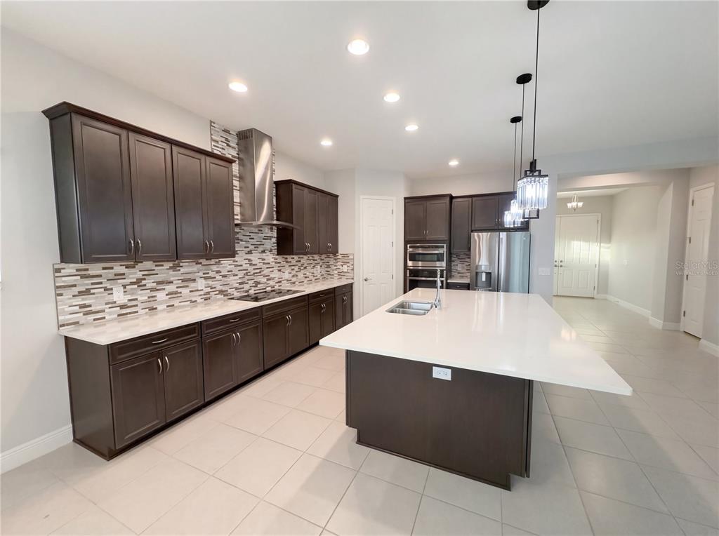 A kitchen features dark wood cabinets, white countertops, a large island, and stainless steel appliances — 11277 RUSTIC TIMBER LOOP, SAN ANTONIO, FL