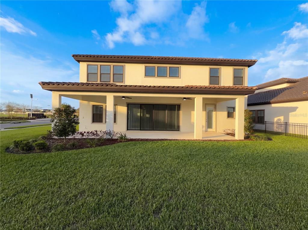 The rear exterior of a two-story house features a covered patio and a grassy lawn — 11277 RUSTIC TIMBER LOOP, SAN ANTONIO, FL