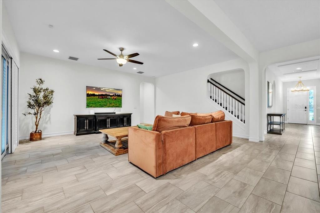 A living room features a brown sectional sofa, a television, and tile flooring — 17923 BARN CLOSE DRIVE, LUTZ, FL